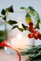 Christmas candle decorated with Vinca minor foliage and Cotoneaster berries