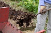 Spreading manure - Forking rotted manure from a trailer 