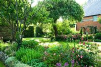 View of immaculate garden with old apple trees, herbaceous borders, beech hedges and roses - Cerne Abbas, Dorset