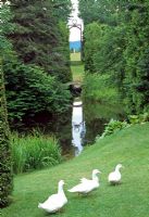 White ducks on the lawn with an impressive vista in the background - Les Jardins de Quatre-Vents, Quebec