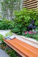 A seating area and raised beds with planting including Betula alba, Hosta, Luzula nivea, Dryopteris, Dicentra 'King of Hearts' and Epimedium in The Eco Chic Garden, sponsored by Helios - Gold medal winner for Best Urban Garden at RHS Chelsea Flower Show 2009