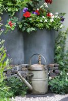 Metal watering can next to lead planters with red, white and blue summer bedding plants. Entente Cordiale, A Touch of France Garden, sponsored by Bonne Maman, Clarke and Spears Clarke and Spears International Ltd, The English Garden Magazine - Silver-Gilt Flora medal winner for Courtyard Garden at RHS Chelsea Flower Show 2009