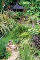 View over middle of garden. Musa basjoo, Phormium tenax 'Tricolour', Butia captita, Phormium cookianun 'Platts Black', Sedum spectabilis and Summerhouse - Beechwell House, South Gloucestershire