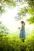 Girl holding bouquet in summer woodland