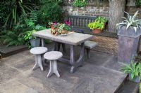 Conran table and stools on raised seating area in a small urban garden 