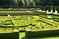 Looking down on the Great Garden at Pitmedden with colourful Buxus - Box -edged parterres infilled with annuals, Taxus baccata - Yew - pyramids and herbaceous borders with trained apples on the walls behind - The National Trust for Scotland
