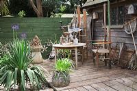 Seaside Inspired garden. Decked area with display of Martin's thrones made from oars, decoy birds, old tools and driftwood. Rusty chain sculpture. Yucca and Agapanthus 'Midnight Star' in pots.
