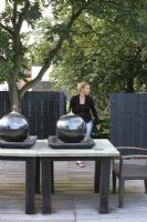 Woman climbing stairs to roof terrace in summer. Large spherical oil burners on table. 