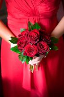 Bouquet of Red roses held by bridesmaid wearing a red dress