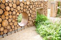 'Narratives of Nature' garden with reclaimed log wall and moon gate. Planting includes ferns, Geranium sylvaticum, Luzula nivea, Atriplex hortensis, Umbilicus rupestris and Betula pubescens. Future gardens, St Albans, Herts  