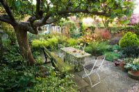 Stone table and garden seating under old apple tree with Yorkstone paving