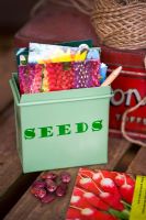 Fairtrade seed tin with seed packets, garden string and Runner bean seed 'Prizewinner stringless' on wooden surface