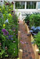 Brick path between raised beds, leading to cold frame and greenhouse - The Marston and Langinger 30th Anniversary Garden at RHS Chelsea Flower Show 2009