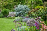 Cottage garden with bench near herbaceous borders