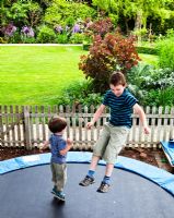 Children on trampoline at Mathern House, Mathern, Monmouthshire, Wales. Early June. Garden opens for National Gardens Scheme.