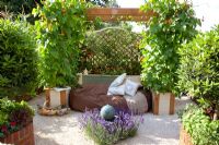 Seating area in vegetable garden with Lavandula 'Hidcote' surrounding a solar-powered water feature and Runner Beans in pots. 'Food for Thought' - Silver Gilt Medal Winner - RHS Hampton Court Flower Show 2010 