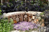 Curved stone and timber bench surrounded by Sambucus nigra 'Black Lace' and Thymus - Thyme. 'It's Only Natural' - Silver Gilt Medal Winner - RHS Hampton Court Flower Show 2010 
 