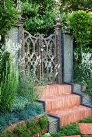 Herringbone tile steps lead up to a carved wooden gate, with rainbow effect water features, plants include Lavandula angustifolia 'Alba', Koeleria glauca and Armeria maritima 'Alba'. 'The Garden Lounge' - Silver Gilt Medal Winner - RHS Hampton Court Flower Show 2010 
 