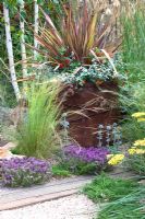 Phormium 'Pink Panther', Geum 'Cooky', Helichrysum petiolare 'Silver' in planter, Lotus berthelotii 'Fire Cracker', recycled crushed ceramic gravel planted with Thyme, Eryngium bourgatii and Betula utilis jacquemontii - 'The Fire Pit Garden' - Silver Medal Winner at the RHS Hampton Court Flower Show 2010 