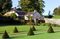 The Walled Garden with pyramids of Taxus baccata and view to the holiday cottages - Plas Cadnant, Menai Bridge, Anglesey, Wales    