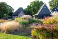 Cottage garden with borders of Salvia verticillata 'Purple Rain', Helenium 'Rubinzwerg', Astrantia major 'Claret', Sesleria nitida, Sedum matrona, Miscanthus malepartus, Panicum virgatum 'Heavy Metal' and Deschampsia cespitosa 