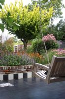 Chequered black and white tiles on a terrace with hanging wooden bench - Hobrede, Holland