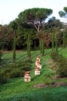 Sloping lawn with urns on plinths. The Field. Il Bosco Della Ragnaia, San Giovanni D'Asso, Tuscany, Italy, October. 
 