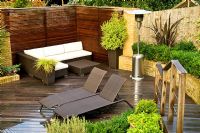 Small urban garden in September with contemporary furniture and patio heater on decking. Raised bed and planting of Lavandula - Lavender and Phormium. Muswell Hill, London