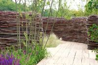 'NEST' - Fencing made from pliable willow and dogwood, 'Stipa tenuissima', Salvia x sylvestris 'Rose Queen' in mixed border - The Future Gardens, St Albans, Herts
