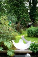 Urban garden showing resin water feature, rectangular pond and curved slate path under metal arch. Yulia Badian garden, London, UK