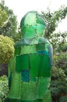 Rear view of green resin figure in border. Yulia Badian garden, London, UK 
