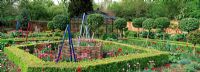 The walled garden with Tulipa, Buxus - Box hedges and decorative tripods at West Green House designed by Marylyn Abbott