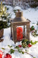 Lantern with red candle, Holly and Ivy on snowy table