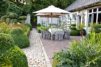 Terrace with dining area next to house and Buxus - Box topiary
