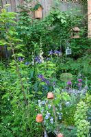 Corner of a small insect and bird friendly urban garden densely planted with flowers and trees. Iris 'Fans Hals', Digitalis purpureum, Viola, Prunus, Primula and Amelanchier.
