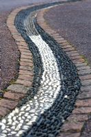 Drainage channel inlaid with black and white pebbles