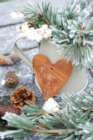 Symphorcarpos albus - Frosted snowberries and pine foliage in a jug with wooden heart and cones