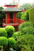 Japanese tea house with pond framed by cloud pruned conifers. The Croft, Yarnscombe, Devon, UK