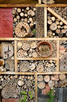 Insect house made from logs, bamboos and straw in clay pot