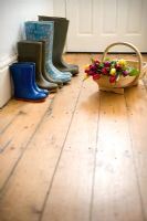 Four pairs of wellies of a gardening family in hallway with a wooden trug of Tulips