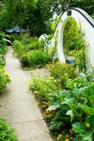 Moon gate marks passage from the kitchen garden to the Wandering Garden, framed by trained fruit trees, Rudbeckias and Tagetes - Marigolds with Lathyrus - Sweet peas beyond. Beggars Knoll, Newtown, Westbury, Wiltshire, UK