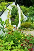 Moon gate marks passage from the kitchen garden to the Wandering Garden, framed by trained fruit trees, Rudbeckias, Agapanthus and Helianthus - Sunflowers. Beggars Knoll, Newtown, Westbury, Wiltshire, UK