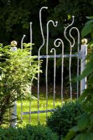 Sun on a metal garden gate with gold balls and curved bars