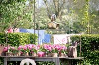 Display of pink Hyacinths in hessian containers on wooden table with sculpture above on metal frame at Bed and breakfast de Lievendael in Velp ,Brabant, Holland
 