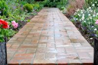 Clay pavers path in large garden after rain shower, Norfolk, England, June