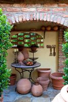 Display of terracotta and decorative metal objects on a bistro table in a gangway. Laurus nobilis