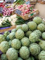Artichokes and vegetables in street market stall, France.