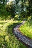 Cobble and brick paths wend their way through informal borders in summer garden - The Corner House, Wiltshire