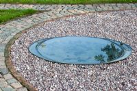 Circular shallow pond surrounded by gravel surface - The Corner House, Wiltshire.