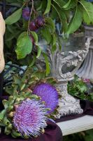 Arrangement in a glass vase with metal pedestal. Plants are Cynara cardunculus and Prunus domestica 